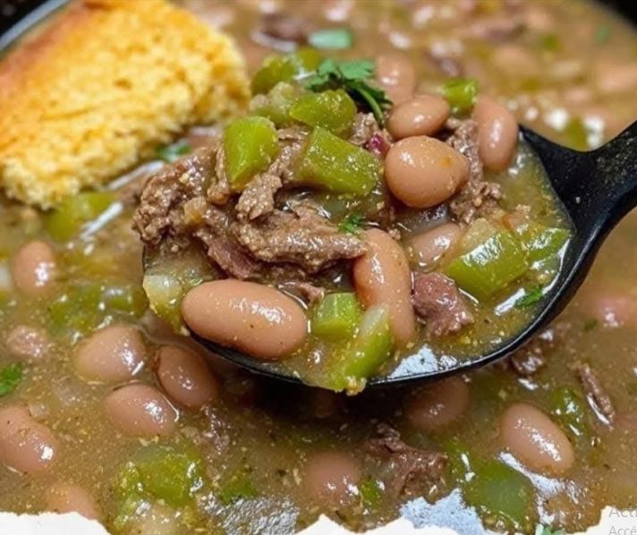A bowl of slow-cooked pinto beans, beef, and green chilies served with cornbread