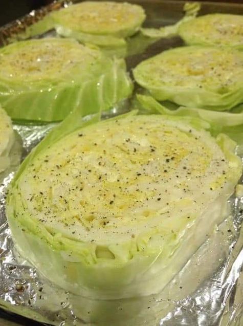 Crispy baked cabbage steaks on a baking sheet, garnished with fresh herbs and Parmesan cheese