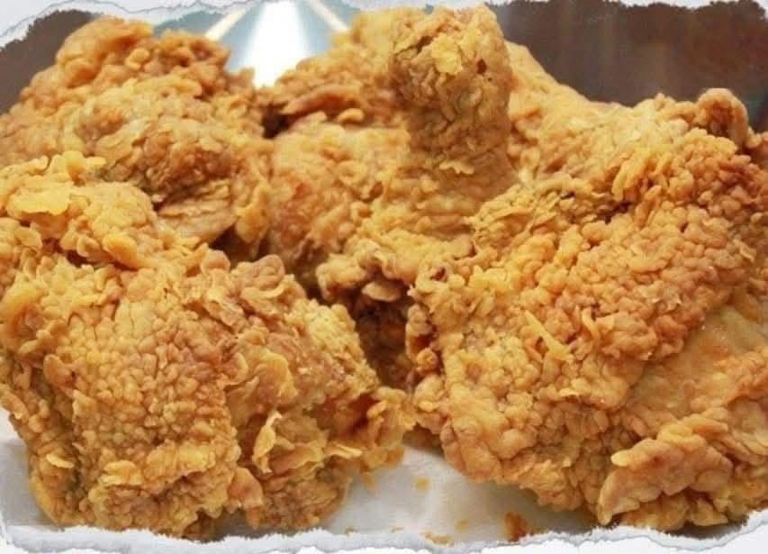Crispy homemade KFC-style fried chicken stacked on a plate, golden-brown and crunchy, served with mashed potatoes and coleslaw