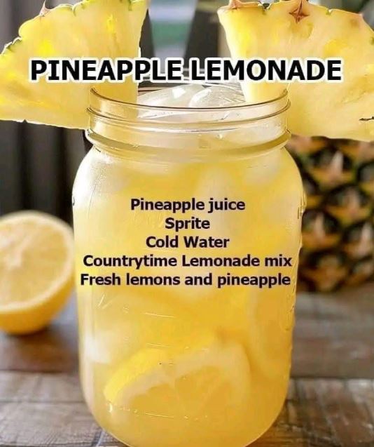 Mason jar filled with pineapple lemonade on ice, garnished with pineapple slices and lemon, sitting on a rustic wooden table